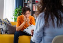 Female psychologist counseling teenage boy in office, Young people's mental health