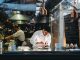 A chef is cooking in his restaurant's kitchen. Shot through the glass. High-end gourmet restaurant.