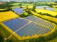 Aerial view, taken by drone, of a solar farm - and many banks of solar panels in a row - in the heart of the rural landscape of southeast England.