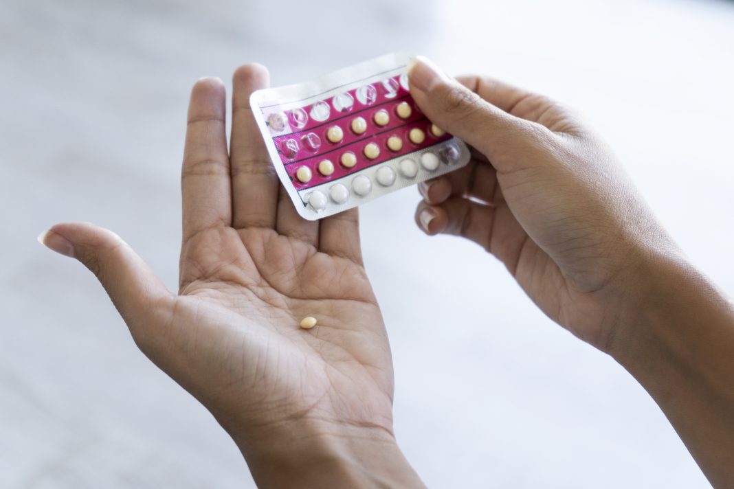 Close-up of young woman's hand holding birth control pills