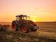 Tractor on the barley field by sunset.