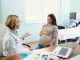 Happy expecting woman communicating with her female gynecologist during a visit in the office.