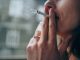 Unrecognizable young woman enjoying a cigarette outdoors. Focus is on the cigarette.
