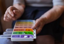 Close up of an old female hands putting pills into plastic containers