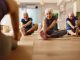 Group of mature people doing stretching exercises with their coach during a Yoga class in a studio. Focus is on senior woman. Copy space.