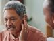 Nurse, man and hearing aid on ear for medical support, wellness and innovation of disability. People, healthcare worker and deaf patient with audiology implant, service or help for sound waves
