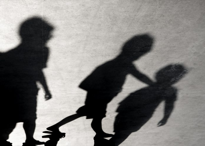 Blurry shadows of three boys friends walking together