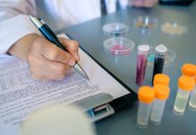 Female scientist hand filling investigation form of small plastic particles on glitter composition