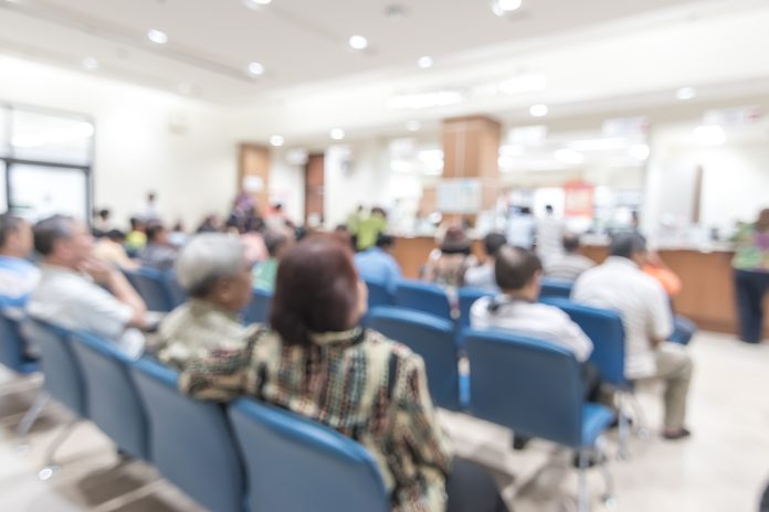 Blur medical background clinic service counter lobby with patient paying bill at cashier desk in hospital