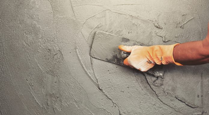 hand of worker plastering cement at wall for building house