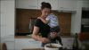 Mother cooking while holding baby toddler child