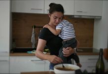 Mother cooking while holding baby toddler child