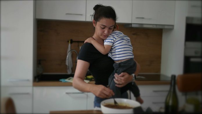 Mother cooking while holding baby toddler child