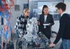 In Robotics Development Laboratory: Black Female Teacher and Two Students Work With Prototype of Robotic Hand. Young Student Telling Something with Smile and Brainstorming with Her Team.