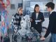 In Robotics Development Laboratory: Black Female Teacher and Two Students Work With Prototype of Robotic Hand. Young Student Telling Something with Smile and Brainstorming with Her Team.