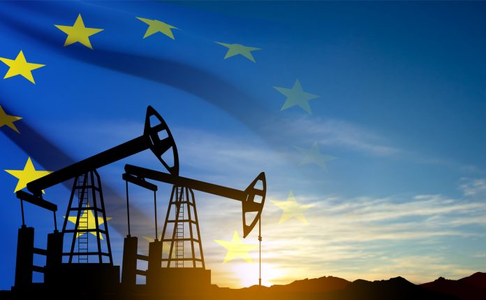 Oil rigs silhouette against sunset ana European union flag