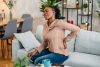 young black woman having back pain while sitting on the sofa at home.