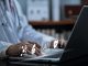 Doctor in a comfortable office using AI on laptop with infographics displayed