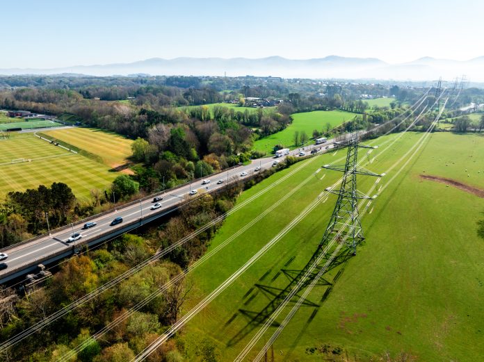 Electricity pylon towering over green fields in north wales