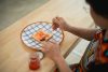 Woman Spreading Jam on Toast in a Bright Kitchen with Checked Plate and Jar of Jam, Close-Up of Hands and Food Preparation Process
