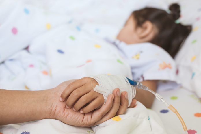 Mother hand holding sick daughter hand who have IV solution bandaged with love and care