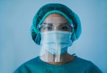 Portrait of young female nurse work inside hospital during coronavirus period - Woman medical worker on Covid-19 outbreak wearing face protective mask