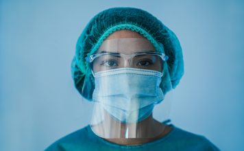 Portrait of young female nurse work inside hospital during coronavirus period - Woman medical worker on Covid-19 outbreak wearing face protective mask