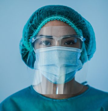 Portrait of young female nurse work inside hospital during coronavirus period - Woman medical worker on Covid-19 outbreak wearing face protective mask