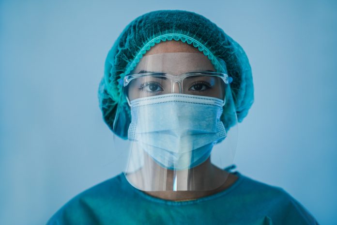 Portrait of young female nurse work inside hospital during coronavirus period - Woman medical worker on Covid-19 outbreak wearing face protective mask