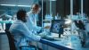 Female Research Scientist with Bioengineer Working on a Personal Computer with Screen Showing Virus Analysis Software User Interface. Scientists Developing Vaccine, Drugs and Antibiotics in Laboratory