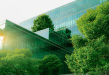 Sustainble green building. Eco-friendly building. Sustainable glass office building with tree for reducing carbon dioxide. Office with green environment. Corporate building reduce CO2. Safety glass.