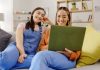 Relax, friends and women with a laptop, sofa and happiness in living room, streaming movies and rest. Female people, joy and girls with technology, happy and search internet on break and laughing