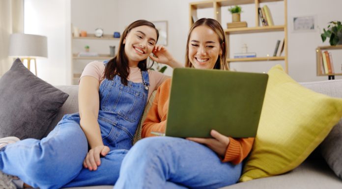 Relax, friends and women with a laptop, sofa and happiness in living room, streaming movies and rest. Female people, joy and girls with technology, happy and search internet on break and laughing