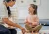 A Physiotherapist sits on the floor with a little girl during a therapy session. She is using toys and various colourful manipulatives to help aid the progress of the Therapy.