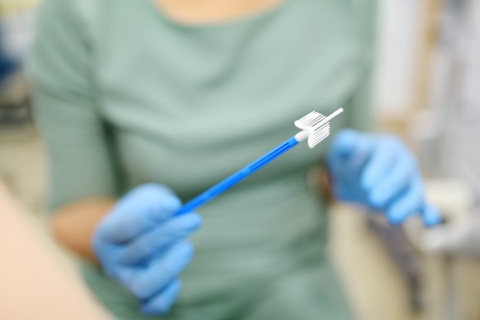 Gynecologist examines a patient takes a smear from a woman cervix. Close up view of doctor hands with gynecological cytobrush. Diagnosis of female viral and infection diseases. Reproductive health.