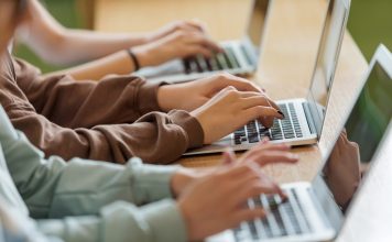 Teenage girls using typing on laptops