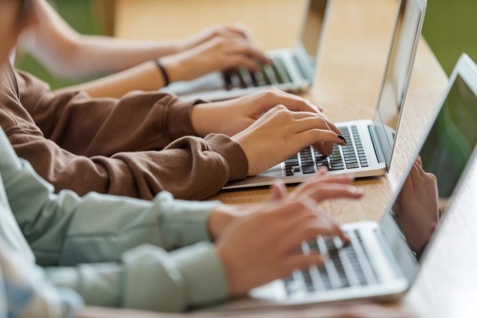 Teenage girls using typing on laptops