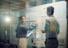 Window, teamwork and whiteboard for brainstorming in meeting, business people with tablet and digital notes with agenda storyboard. Information, ideas with research and calendar for project schedule