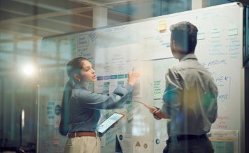 Window, teamwork and whiteboard for brainstorming in meeting, business people with tablet and digital notes with agenda storyboard. Information, ideas with research and calendar for project schedule