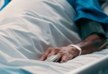 Elderly man, hand and recovery on bed hospital for pulse monitor, healthcare treatment and healing from surgery. Senior, male patient and sleep, emergency icu and chronic disease for wellness
