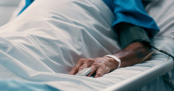 Elderly man, hand and recovery on bed hospital for pulse monitor, healthcare treatment and healing from surgery. Senior, male patient and sleep, emergency icu and chronic disease for wellness
