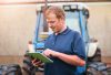 Production, farmer and man with tablet by tractor for schedule, checklist and research on industry. Farming, website and male person with tech for agriculture, agro app and reading weather info