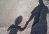 Shadow Of Mother With Son Standing On Road