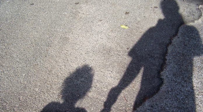 Shadow Of Mother With Son Standing On Road