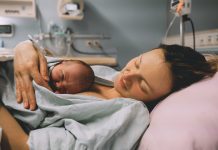 Mother and newborn. Child birth in maternity hospital. Young mom hugging her newborn baby after delivery. Woman giving birth. First moments of baby life after labor.