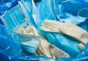 Medical trash. Coronavirus protection equipment in medical waste bin. Used face masks and sterile gloves. Doctor uniform for patient treatment in hospital. Prevention the spread of COVID-19.