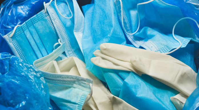 Medical trash. Coronavirus protection equipment in medical waste bin. Used face masks and sterile gloves. Doctor uniform for patient treatment in hospital. Prevention the spread of COVID-19.