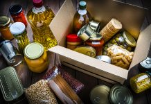 Cardboard box filled with non-perishable foods on wooden table. High angle view.
