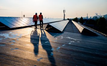 Male engineers walking along rows of photovoltaic panels
