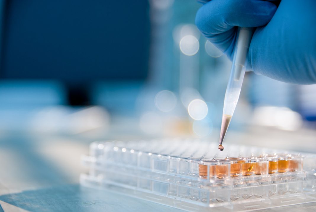 Lab technician injecting liquid into a microtiter plate